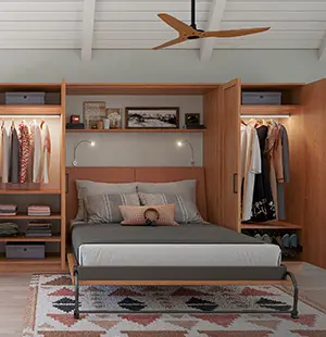 Modern bedroom with a Murphy bed surrounded by custom wood cabinetry and open closets, featuring folded clothes, hanging garments