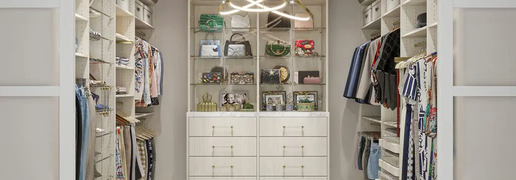 Custom walk in closet with white drawers and glass display shelving Closet Factory Greenville