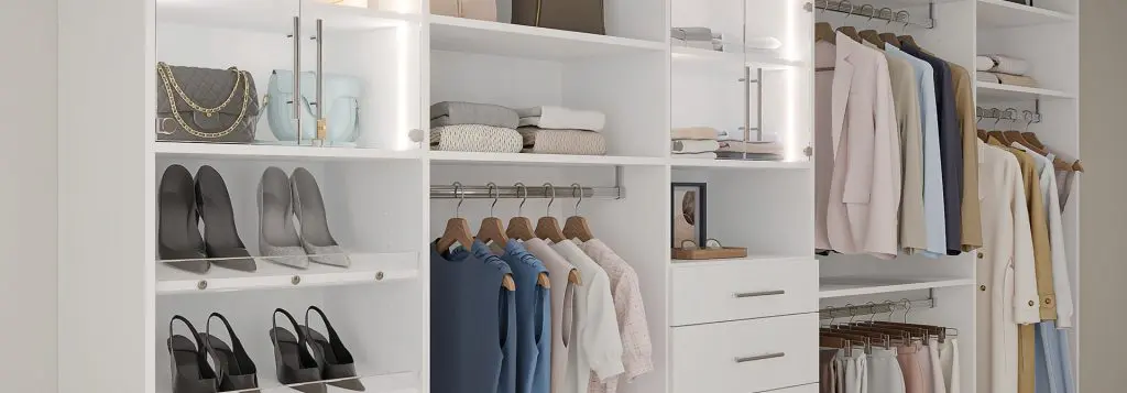 Modern walk-in closet with white cabinetry, glass cabinet doors, hanging rods, and open shelves showcasing neatly organized clothing
