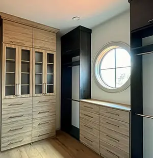 Walk in closet with glass front cabinet doors and built in vanity drawers