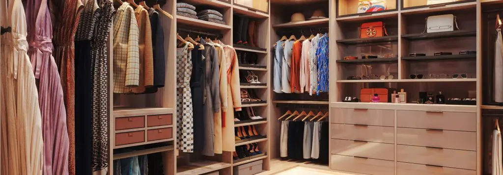 Luxurious walk-in closet with soft lighting, ample storage for shoes and accessories, and coordinated hanging sections for dresses, blouses, and outerwear