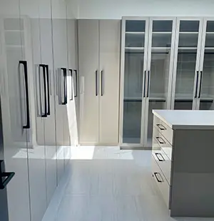 Custom walk-in closet with Island with pull-out accessory drawers and glass doors