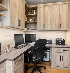 Warm, wood-toned home office with custom cabinetry, L-shaped desk, and dual computer monitors