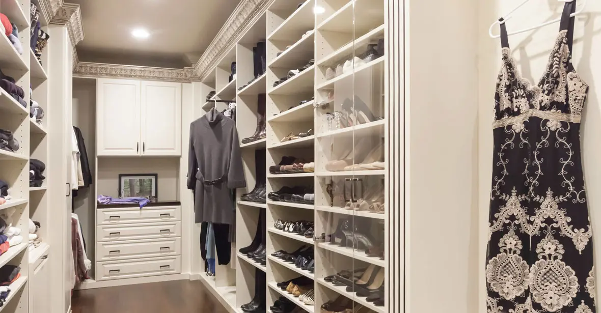 Custom walk-in closet with white cabinetry, shoe shelving, drawers, and organized hanging storage.