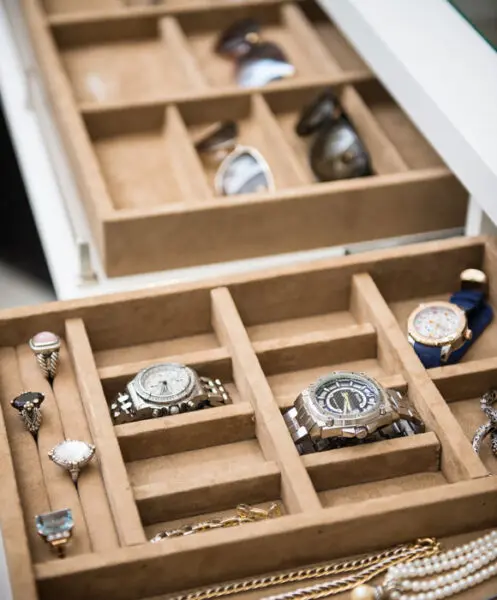 High-end accessory organization by Closet Factory showing tiered tan velvet trays designed to showcase luxury watches and fine jewelry within a white custom closet.