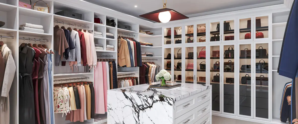 Luxury custom walk-in closet with white shelving, double hanging sections, glass-front handbag cabinets, and a marble-topped center island with drawers.