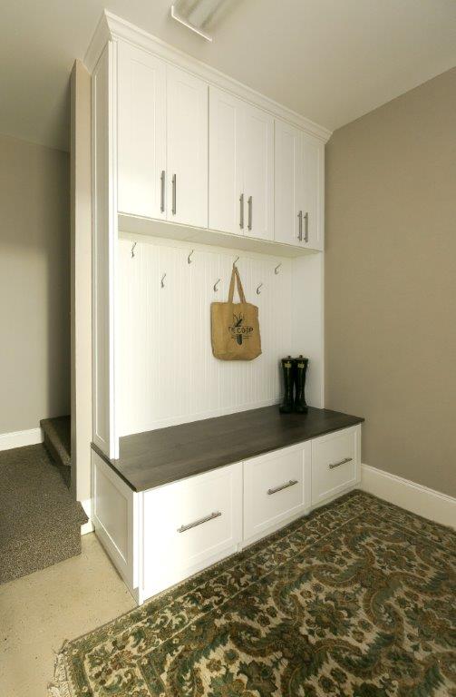 A mudroom with hooks and a green rug