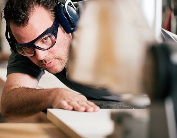 man on sliding table saw in factory making closet pieces for a closet system