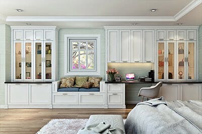 Shaker style wall unit in bedroom has glass cabinets for handbag display.