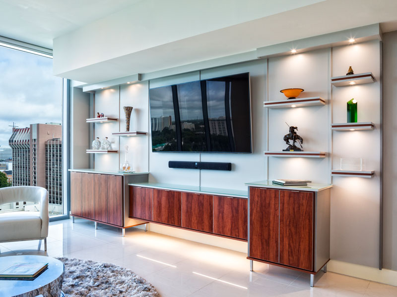 Modern entertainment center in living room has custom designed base cabinets in a wood grain.