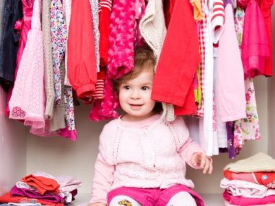 little girl sits on the closet floor