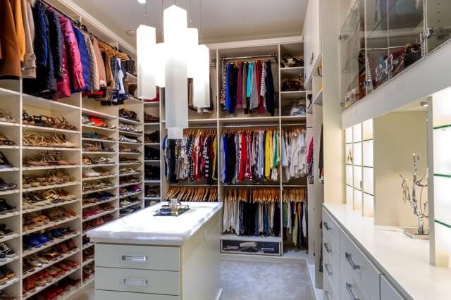 A full walk-in closet  with a white chandelier and island
