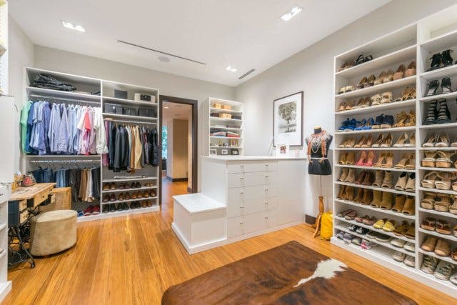 A walk-in closet with numerous shoe racks and hanging space