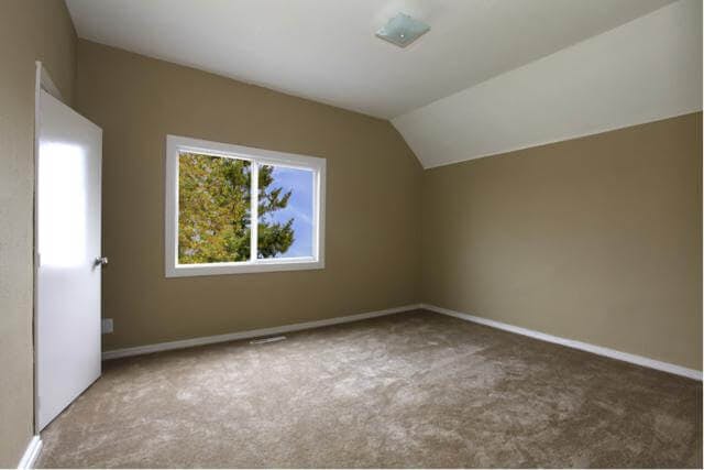an empty top story room. A window looks out onto evergreens. 