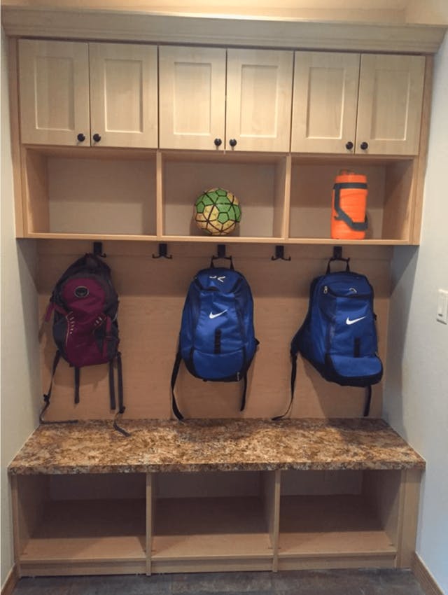 A mudroom with kids sports bags hanging from hooks