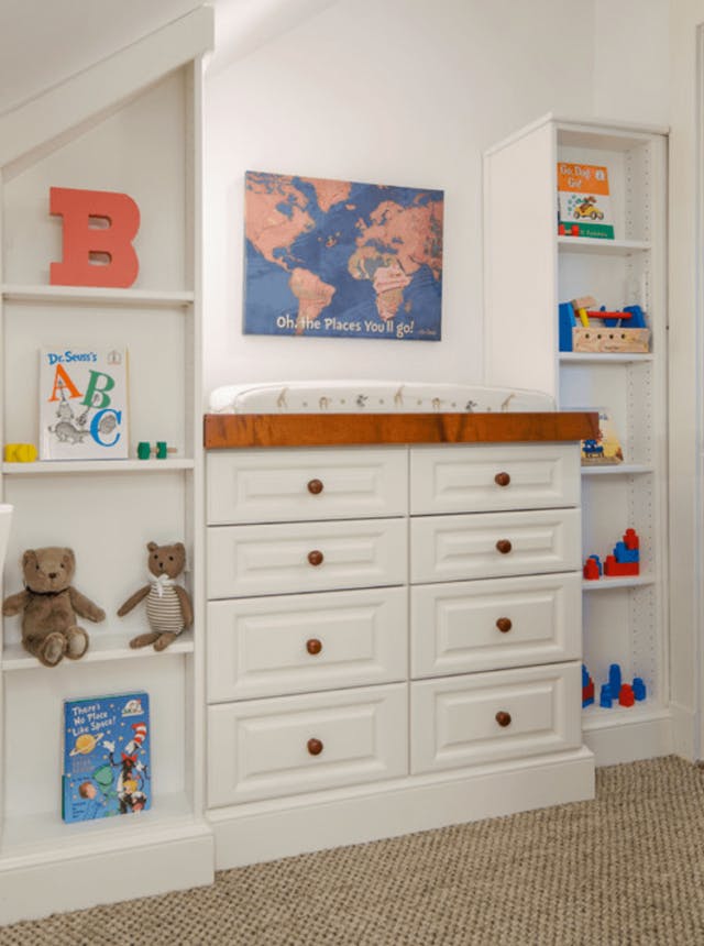 A baby changing table with cabinets next to it