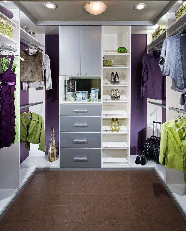 A purple closet with green items hanging within