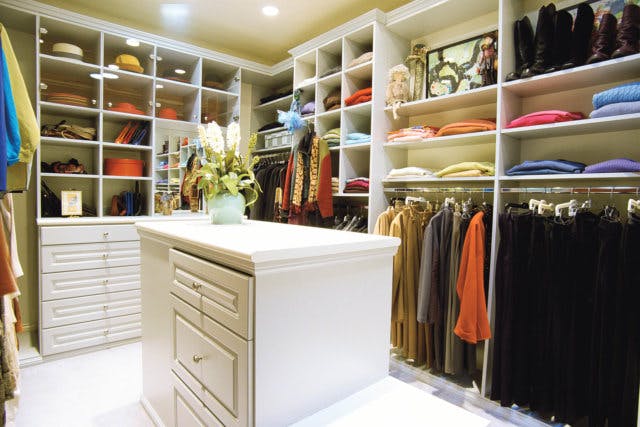 A well lit walk-in closet with plenty of hanging space and shelves