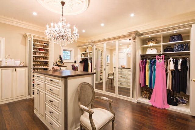 A white walk-in closet with island and chair