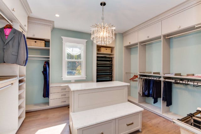 A walk-in closet with two tiered hanging space