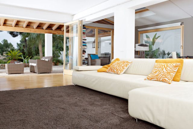 A white couch with yellow pillows on an enclosed porch