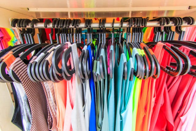 Many colorful clothes hanging in a closet