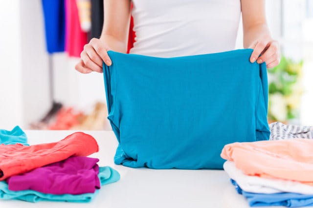 A woman folds a blue shirt