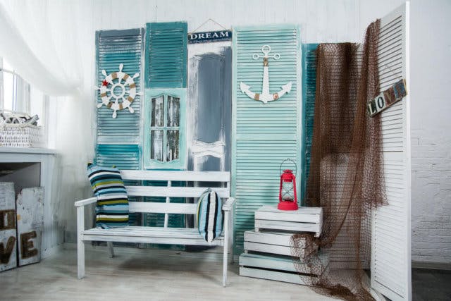 A white room with a white bench, decorated with shutters painted blue