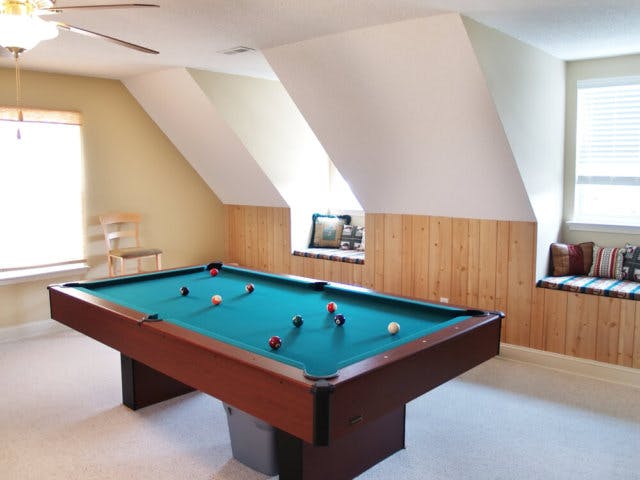 A pool table in a top story room with dormers