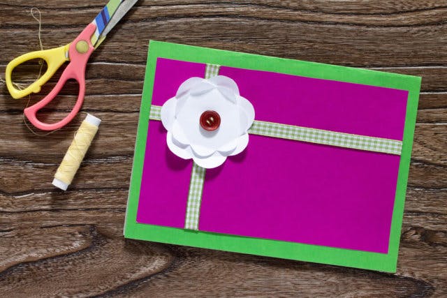 A pair of scissors and a roll of string sit next to a hand-made letter