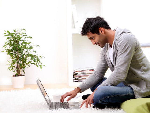 Young man sitting on a carpet using a laptop