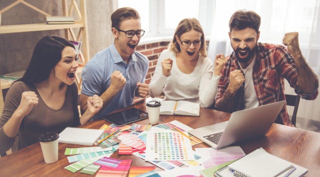 Four people looking very excitedly at a computer