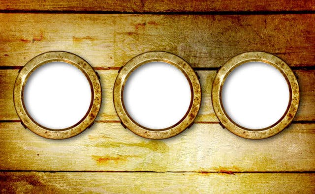 A set of three portholes on a wooden surface