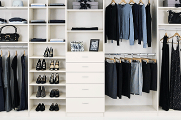 white reach-in closet with hanging and folded clothing