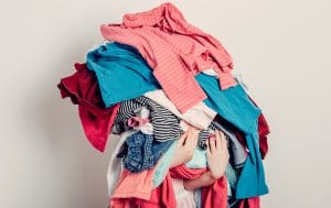 A woman holding a pile of clothes she is getting rid of