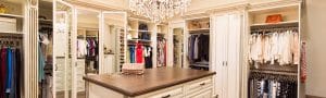 A walk-in closet with chandelier and island