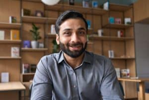 A man looking at the camera in front of a shelving unit