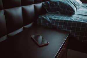 A dark bedside table with a phone resting on it