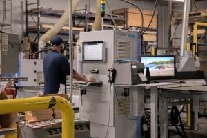 A workman operates a CNC machine