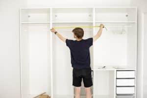 Man holding tape measure up to closet