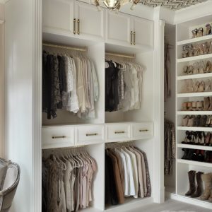 White custom closet shelving, open shelving for shoes, and dual hanging sections for a curated wardrobe display.