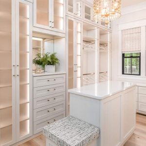 Luxury closet withLED-lit shelving, Raised Panel drawers, a mirrored vanity, and adjustable shoe fences.