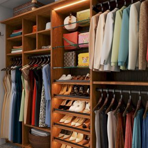 Built-in custom closet Rustic Cherry melamine with glass shelving, angled shoe shelves, and triple-hang wardrobe rods. Integrated lighting and cubby storage maximize space and visibility.