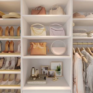 Soft neutral-toned boutique-style closet with white built-ins, open shelving for shoes, purses, and hats