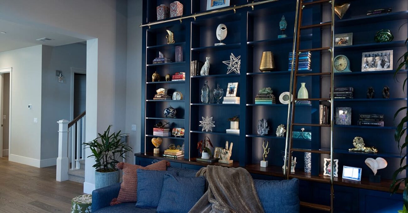 Library book case with strip lighting and rolling ladder in navy blue