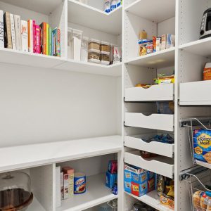 White walk-in pantry featuring pull-out drawers, vertical wine storage, and open shelving for dry goods and small appliances.