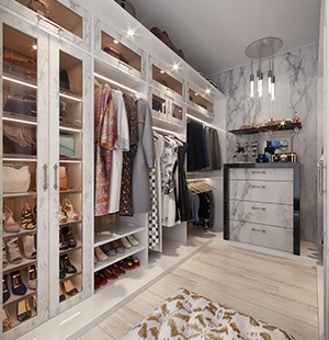 Elegant walk-in closet with marble-finished cabinetry, glass-front doors, and built-in lighting, showcasing organized clothing, shoes, and accessories on light wood floors