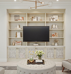 Custom built-in media center with open shelving, decorative lower cabinets, and a central mounted TV