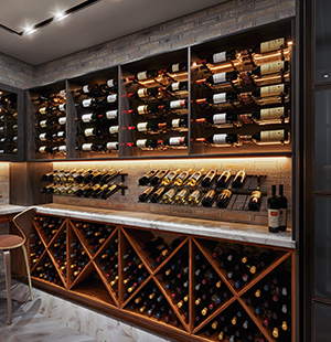 Custom wine room with open bottle displays, marble countertop, and under-cabinet lighting