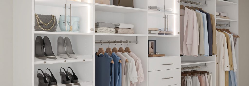 Modern walk-in closet with white cabinetry, glass cabinet doors, hanging rods, and open shelves showcasing neatly organized clothing